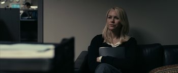 Movie still from “Fair Game” (2010), directed by Doug Liman – A woman sitting on a couch holding a book; Medium shot, Over the shoulder angle