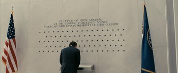 Movie still from “Fair Game” (2010), directed by Doug Liman – A man standing in front of a white wall; Wide shot, Low angle