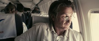 Movie still from “Fair Game” (2010), directed by Doug Liman – A man sitting on a plane with his eyes closed; Close Up shot, Low angle