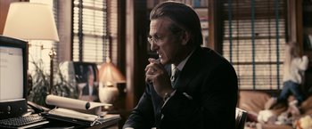 Movie still from “Fair Game” (2010), directed by Doug Liman – A man sitting at a desk in front of a lamp; Medium shot, Over the shoulder angle