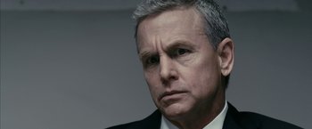 Movie still from “Fair Game” (2010), directed by Doug Liman – An older man in a white shirt and a black suit; Close Up shot, Low angle