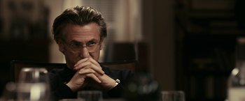 Movie still from “Fair Game” (2010), directed by Doug Liman – A person sitting at a table with his hands together; Close Up shot, Over the shoulder angle