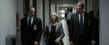 Movie still from “Fair Game” (2010), directed by Doug Liman – A woman walking down a hallway with two other men; Medium shot, Over the shoulder angle