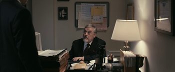 Movie still from “Fair Game” (2010), directed by Doug Liman – An older man sitting at a desk in front of a laptop computer; Medium shot, Over the shoulder angle