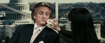 Movie still from “Fair Game” (2010), directed by Doug Liman – A man in a business suit is being fitted for a tie; Close Up shot, Over the shoulder angle