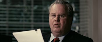 Movie still from “Fair Game” (2010), directed by Doug Liman – A man in a suit and tie holding a piece of paper; Close Up shot, Over the shoulder angle