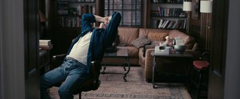 Movie still from “Fair Game” (2010), directed by Doug Liman – A man sitting in a chair in a living room; Wide shot, High angle