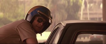 Movie still from “Falling Down” (1993), directed by Joel Schumacher – A man wearing a helmet sitting in the back of a car; Close Up shot, Low angle