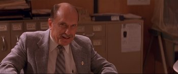 Movie still from “Falling Down” (1993), directed by Joel Schumacher – An older man in a suit and tie smiling for the camera; Close Up shot, High angle