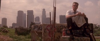 Movie still from “Falling Down” (1993), directed by Joel Schumacher – A man sitting on top of a concrete structure; Wide shot, Low angle