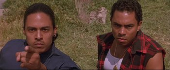 Movie still from “Falling Down” (1993), directed by Joel Schumacher – A couple of people sitting next to each other on a field; Close Up shot, Low angle