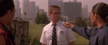 Movie still from “Falling Down” (1993), directed by Joel Schumacher – An older man is being fitted for a tie by an older man; Medium shot, Over the shoulder angle