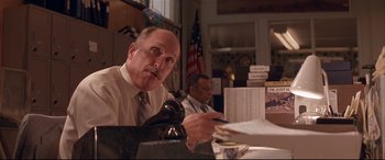 Movie still from “Falling Down” (1993), directed by Joel Schumacher – A man sitting in front of a phone and another man sitting in front of papers; Medium shot, Low angle