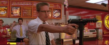 Movie still from “Falling Down” (1993), directed by Joel Schumacher – A man holding a gun while standing in front of a counter; Medium shot, Low angle
