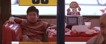 Movie still from “Falling Down” (1993), directed by Joel Schumacher – A man sitting in front of a tv at a fast food restaurant; Medium shot, Low angle