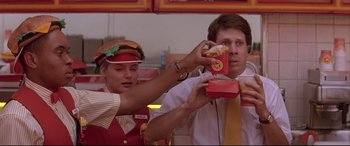 Movie still from “Falling Down” (1993), directed by Joel Schumacher – A man and a woman holding a box of hot dogs in front of him; Medium shot, Overhead angle