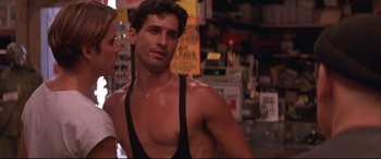 Movie still from “Falling Down” (1993), directed by Joel Schumacher – A man in a tank top is standing next to a woman; Medium shot, Over the shoulder angle