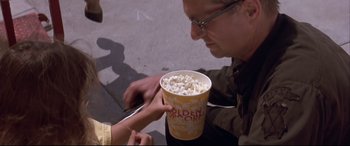 Movie still from “Falling Down” (1993), directed by Joel Schumacher – A man holding a bucket full of popcorn; Close Up shot, Over the shoulder angle