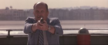 Movie still from “Falling Down” (1993), directed by Joel Schumacher – A man in a suit and tie is holding a gun; Medium shot, Low angle