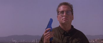 Movie still from “Falling Down” (1993), directed by Joel Schumacher – A man holding a blue toy gun while wearing glasses; Close Up shot, Low angle