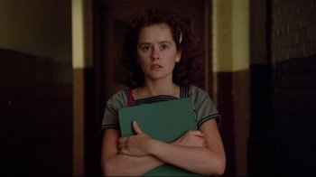 A young woman holding a green book in her arms