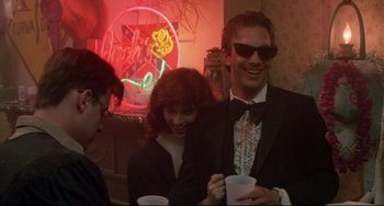 Movie still from “Fandango” (1985), directed by Kevin Reynolds – A man and a woman are standing next to each other holding cups; Medium shot, Low angle