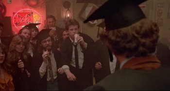 Movie still from “Fandango” (1985), directed by Kevin Reynolds – A group of people standing in a room drinking coffee; Wide shot, Over the shoulder angle