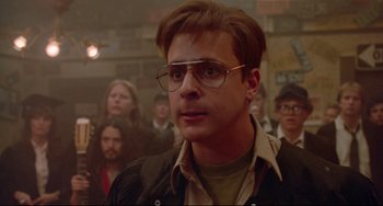 Movie still from “Fandango” (1985), directed by Kevin Reynolds – A man in a crowd of people wearing glasses; Close Up shot, Low angle