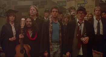 Movie still from “Fandango” (1985), directed by Kevin Reynolds – A group of people standing next to each other in a room; Medium shot, Low angle