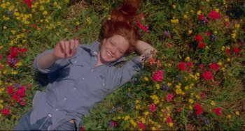 Movie still from “Fandango” (1985), directed by Kevin Reynolds – A woman laying in a field of flowers; Medium shot, Overhead angle