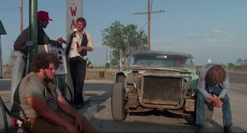 Movie still from “Fandango” (1985), directed by Kevin Reynolds – An older man standing next to an old car; Wide shot, Low angle