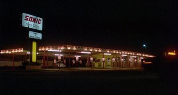 Movie still from “Fandango” (1985), directed by Kevin Reynolds – A neon sign is lit up at night in front of a diner; Extreme Wide shot, Low angle