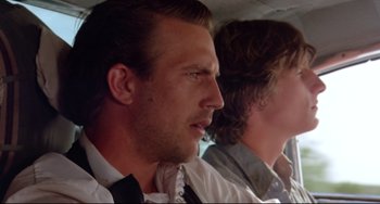 Movie still from “Fandango” (1985), directed by Kevin Reynolds – Two men in a car looking into the distance; Close Up shot, Over the shoulder angle