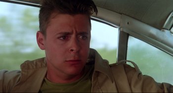 Movie still from “Fandango” (1985), directed by Kevin Reynolds – A man sitting in a car with his eyes wide open; Close Up shot, Low angle