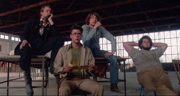 Movie still from “Fandango” (1985), directed by Kevin Reynolds – A group of people sitting on chairs in a room; Medium shot, Low angle