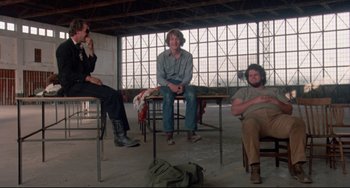 Movie still from “Fandango” (1985), directed by Kevin Reynolds – A group of people sitting on top of a wooden table; Wide shot, Low angle