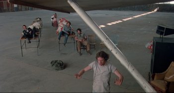 Movie still from “Fandango” (1985), directed by Kevin Reynolds – A group of people sitting and standing in a room; Wide shot, High angle