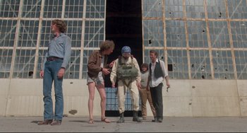 Movie still from “Fandango” (1985), directed by Kevin Reynolds – A group of people standing outside of a building; Wide shot, Low angle