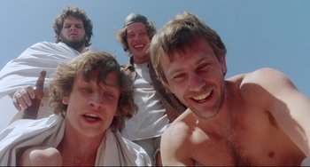 Movie still from “Fandango” (1985), directed by Kevin Reynolds – A group of young men standing next to each other; Medium shot, Low angle
