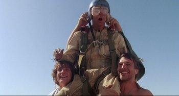Movie still from “Fandango” (1985), directed by Kevin Reynolds – A man is sitting on top of another man's shoulders; Medium shot, Low angle