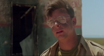 Movie still from “Fandango” (1985), directed by Kevin Reynolds – A young man wearing glasses and a tan jacket; Close Up shot, Low angle