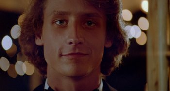 Movie still from “Fandango” (1985), directed by Kevin Reynolds – A young man's face with long brown hair; Close Up shot, Low angle