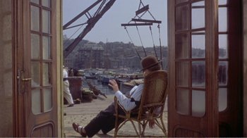 Movie still from “Fanny” (1961), directed by Joshua Logan – An old man sitting in a chair on a pier; Wide shot, High angle