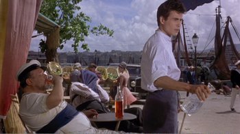 Movie still from “Fanny” (1961), directed by Joshua Logan – A man standing in front of a group of people; Medium shot, Low angle