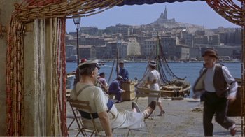Movie still from “Fanny” (1961), directed by Joshua Logan – A group of people sitting on a beach near the water; Wide shot, High angle