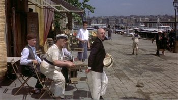 Movie still from “Fanny” (1961), directed by Joshua Logan – A group of men standing next to each other on a sidewalk; Wide shot, High angle