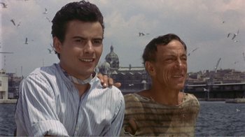 Movie still from “Fanny” (1961), directed by Joshua Logan – Two men standing next to each other in front of a building; Close Up shot, Low angle