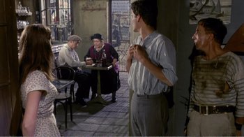 Movie still from “Fanny” (1961), directed by Joshua Logan – A group of people sitting at tables in a room; Wide shot, Over the shoulder angle
