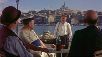 Movie still from “Fanny” (1961), directed by Joshua Logan – A group of men sitting on a pier with a city in the background; Wide shot, High angle