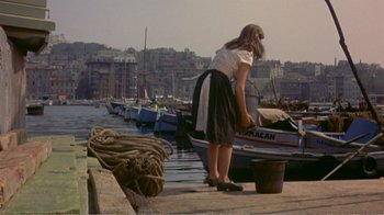 Movie still from “Fanny” (1961), directed by Joshua Logan – A woman standing next to a boat in a harbor; Wide shot, High angle